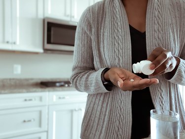 close view of a woman in her kitchen taking an anti-anxiety medication like zoloft