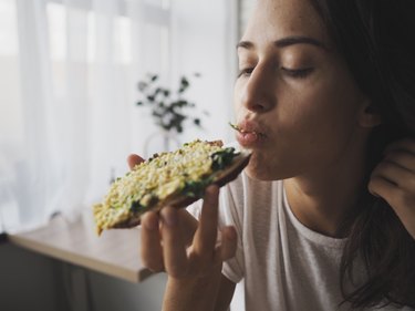 特写一个年轻的白人女人运动前吃鳄梨面包