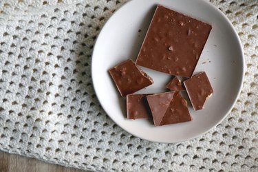 Plate of chocolate on white blanket to show the link between chocolate, caramel and acid reflux