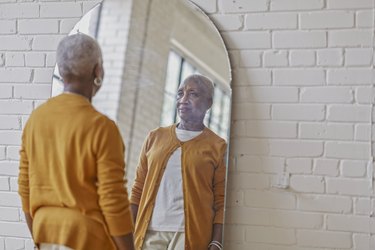 Woman looking in mirror to see weight-loss results