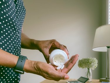 Close-Up of Woman Pouring Pills into Palm of Hand, as a way to get rid of period cramps