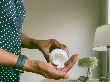 Close-Up of Woman Pouring ibuprofen pills into her hand