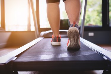 close up of the back of a person's calves and feet in sneakers walking on a treadmill