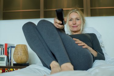 Mature woman watching TV in bed