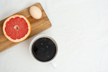 Cup of coffee, half of grapefruit and hard-boiled egg on wooden platter to show diet results, egg diet before and after, and 2-week egg diet menu schedule