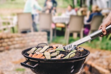 Closeup of someone grilling vegetables on a small charcoal grill