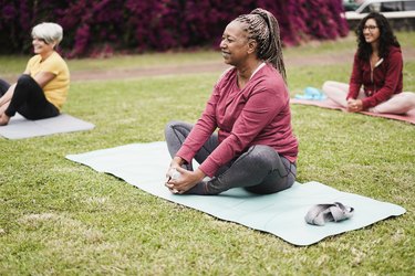 women doing the butterfly stretch outside on yoga mats on the grass