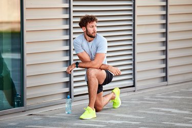 young caucasian man doing a half-kneeling hip flexor stretch for tight hips