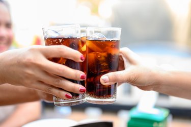 a closeup of two people clinking classes of diet soda together