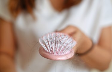 close view of a pink hairbrush filled with hair strands, to represent normal daily hair loss