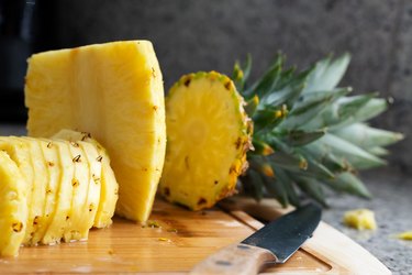 Sliced pineapple on wooden board in kitchen