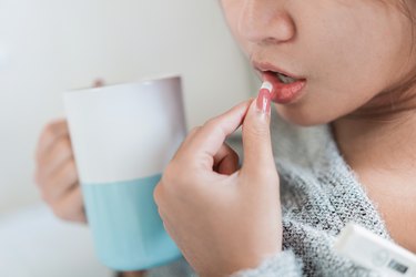 Close-Up Of Woman Taking antidepressant holding mug of caffeinated coffee