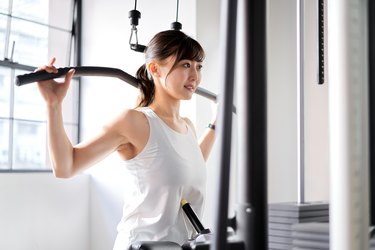 Fitness Asian Woman Working Out Shoulder Pull Down At Gym. Girl