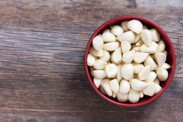 peeled cloves of garlic on an old wooden background closeup top view with space for text