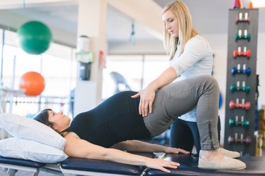 pregnant woman doing glute bridge diastasis recti exercise with a physical therapist