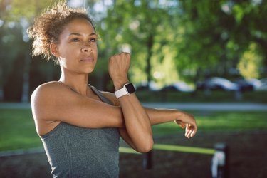Athletic Black woman stretching her arms outside