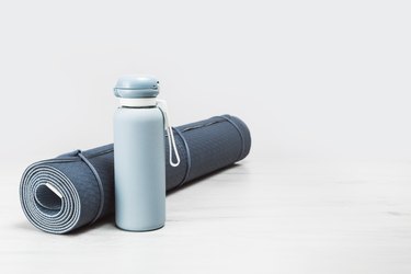 Rolled yoga mat and blue water bottle, which can be a great substitute for dumbbells.