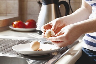 Hard-boiled eggs being shelled in kitchen