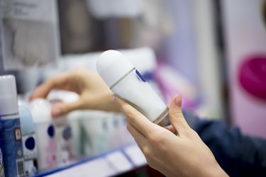 person's hands holding a stick of deodorant in the store