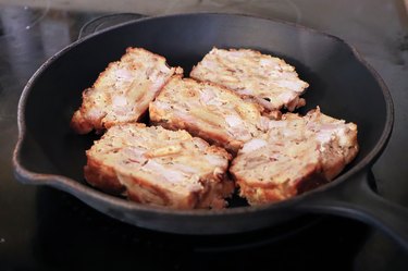 Frying scrapple slices on a cast iron pan on stove