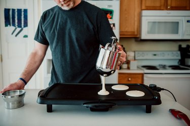 Person Pouring Pancake Batter Onto a Griddle