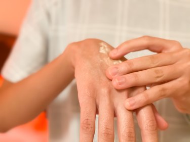 mixed-race young female lotions her dry hands before bed