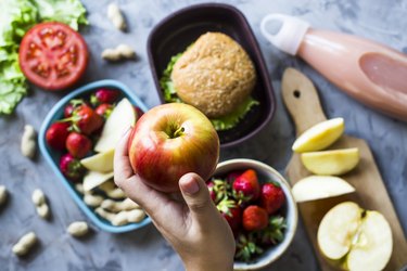 top view of a person holding an apple above other foods, as a way to relieve heartburn