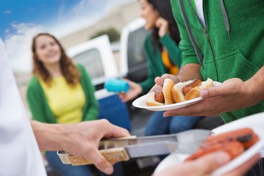 Group of people cooking hots dogs and keeping them warm for a fundraiser outside