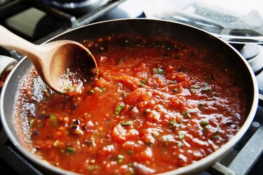 Preparing fresh tomato sauce in pan in a kitchen