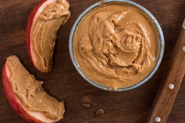 top view of a bowl of peanut butter and apple slices covered in peanut butter