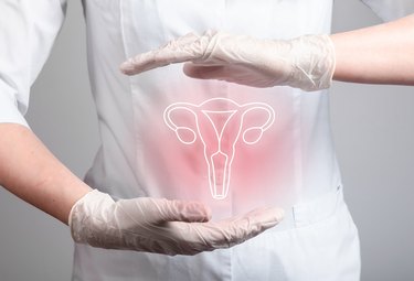female doctor with pink and white symbol of ovaries and uterus between gloved hands