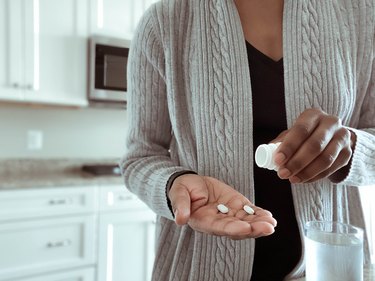 Person taking an over-the-counter pill for depression, in their kitchen