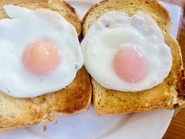 Overhead shot of eggs sunny-side up style on toast on a white plate, as an example of foods high in lecithin