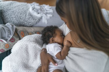 top view of a person with long brown hair breastfeeding a very young baby