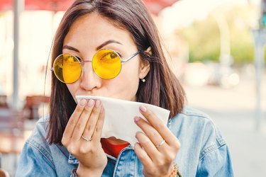 Asian woman wiping her mouth because she has upper lip sweat