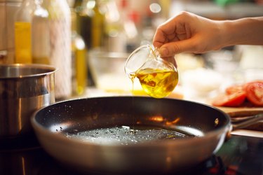 hand pouring cooking oil on a skillet