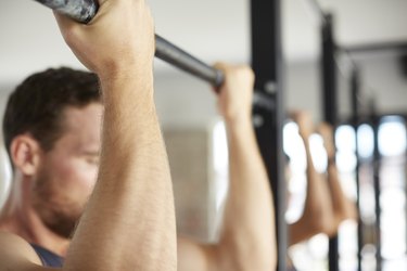 close up of a man's hands holding a chin-up bar with an underhand grip