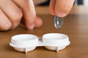 hand taking a contact out of a contact lens case