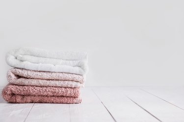 a stack of clean washcloths on a wooden surface, to represent compresses for treating pink eye at home