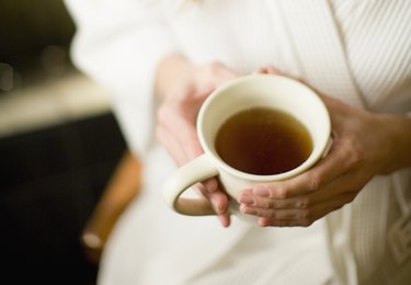 Woman holding cup of peppermint tea for gas pain relief