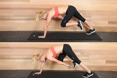 Woman performing tripos bear crawl ab exercise.