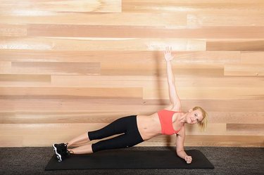 Woman performing side plank ab exercise.