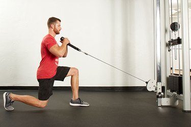 Man performing cable forward lunge on the cable machine