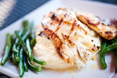 Grilled white fish on top of mashed potatoes and green beans