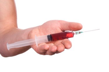 Syringe of blood placed on a hand over a white background