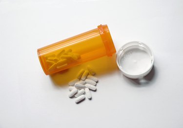 top down photo of an orange prescription bottle with white tablets