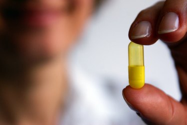 close up of hand holding yellow pill