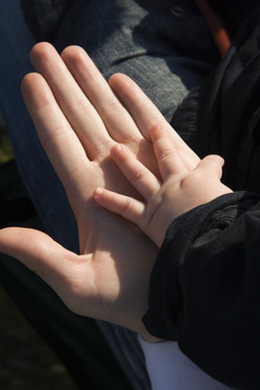 A child's hand is placed on top of an adult's hand.