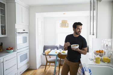 Man eating cereal and looking away in kitchen