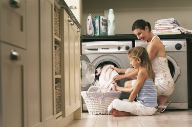 Girl (7-9) helping mother with laundry, smiling
